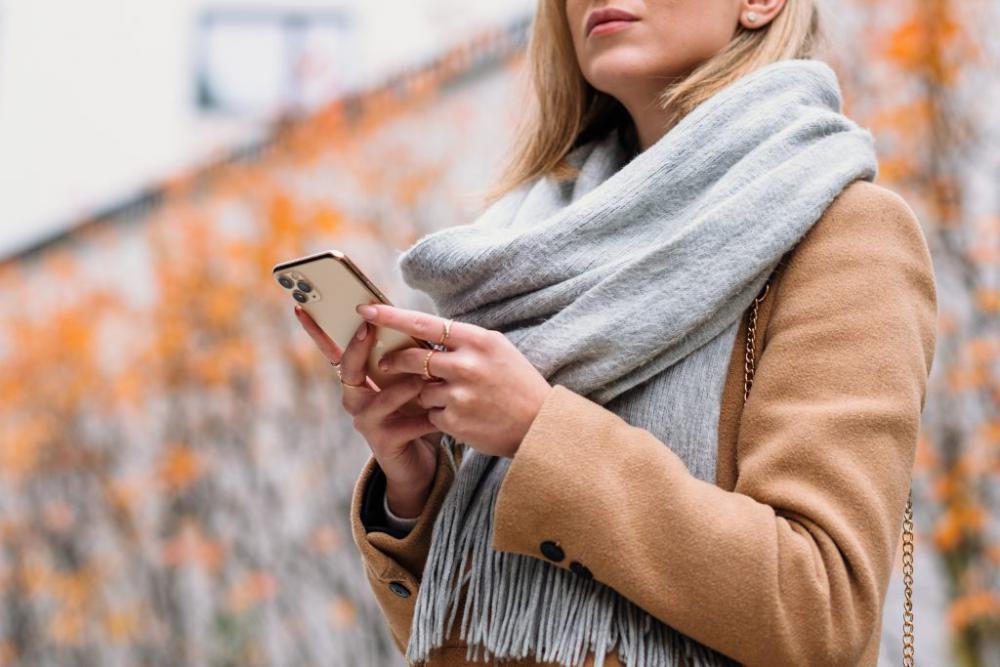 Female holding her phone on an autumn day closeup Female holding her phone on an autumn day closeup