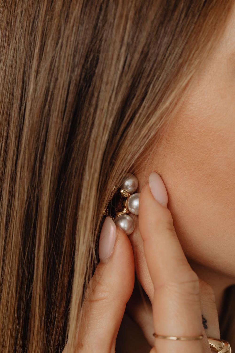 Details of gold jewelry - beautiful woman wearing a tan silk shirt Details of gold jewelry - beautiful woman wearing a tan silk shirt