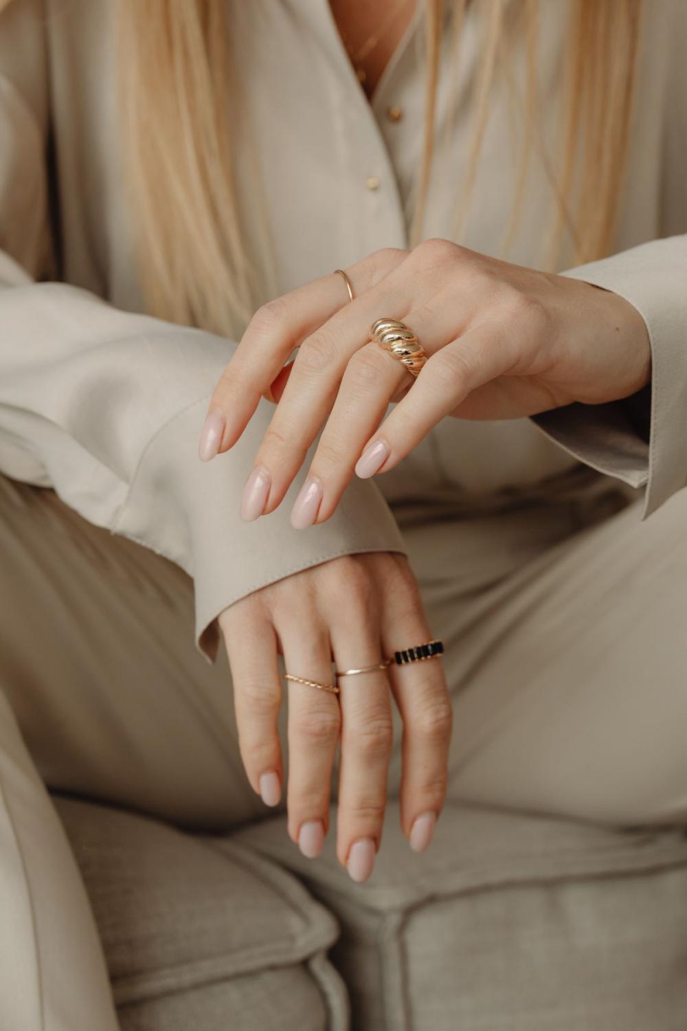 Details of gold jewelry - beautiful woman wearing a tan silk shirt Details of gold jewelry - beautiful woman wearing a tan silk shirt
