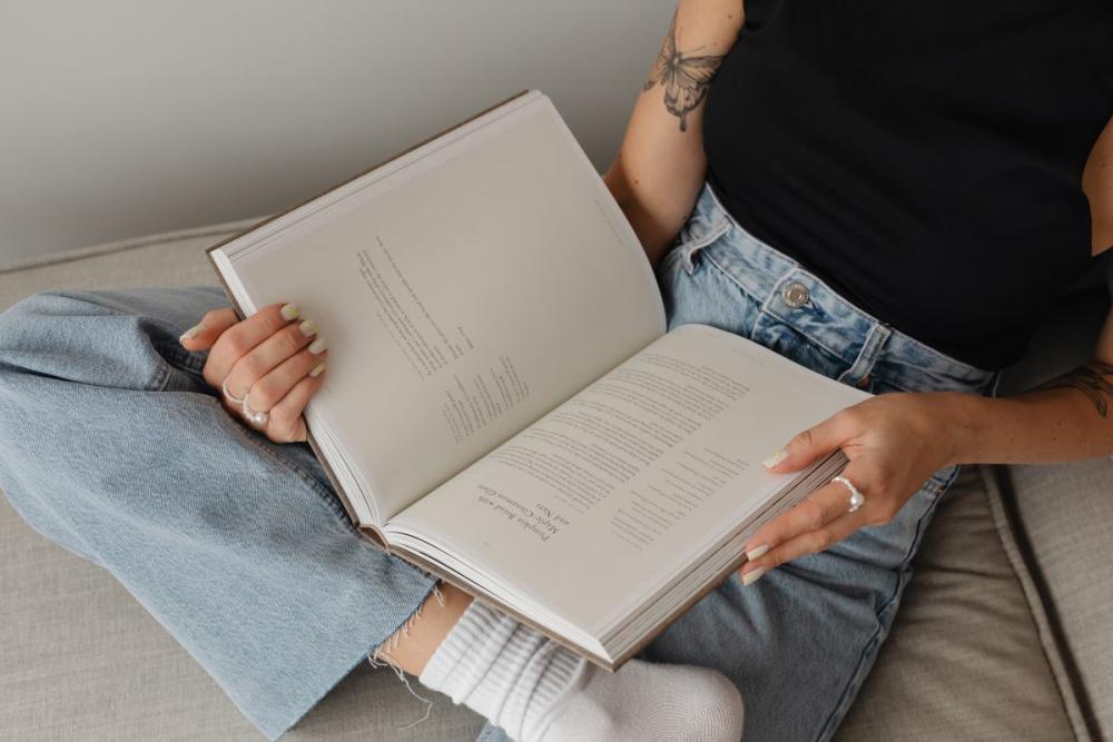 Woman in light-colored jeans with books Woman in light-colored jeans with books