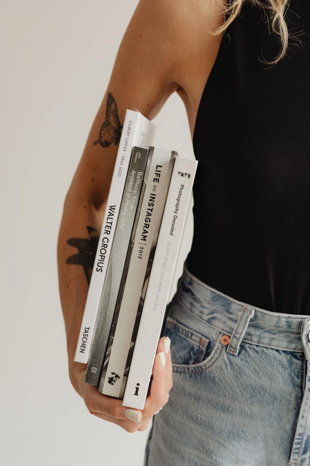 Woman in light-colored jeans with books Woman in light-colored jeans with books