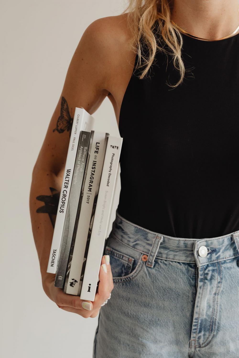 Woman in light-colored jeans with books Woman in light-colored jeans with books
