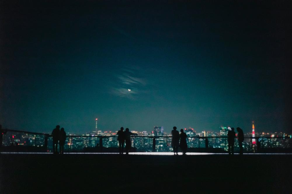 Silhouetted Couples Look Out At A City At Night Photo Silhouetted Couples Look Out At A City At Night Photo