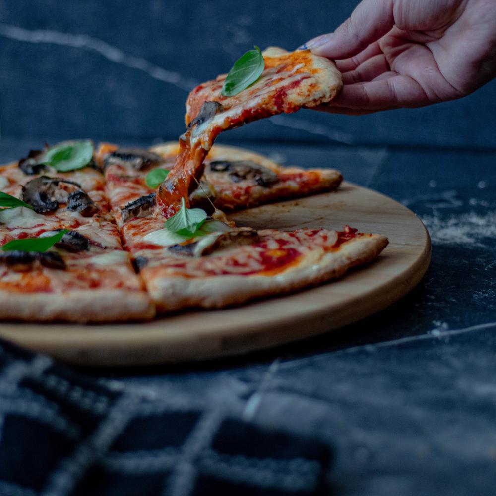 Persons Hand Lifts A Slice Of Pizza From Round Plate Photo Persons Hand Lifts A Slice Of Pizza From Round Plate Photo