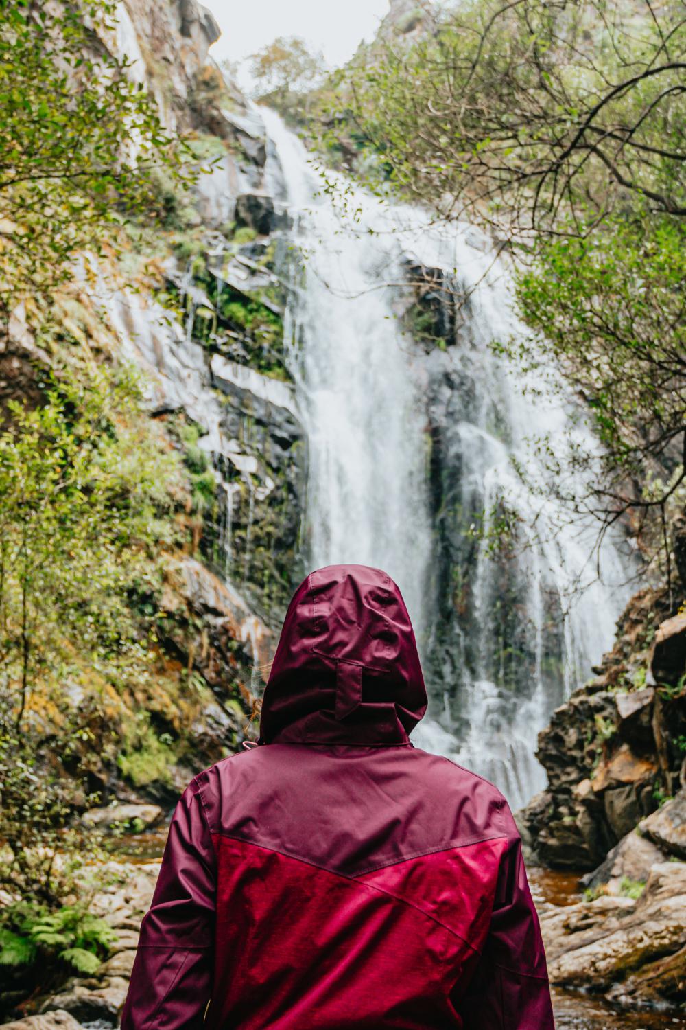 Person In Red Raincoat Admires A Huge Waterfall Photo Person In Red Raincoat Admires A Huge Waterfall Photo