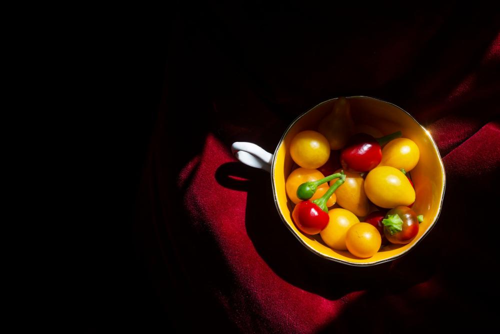 Tea Cup With Hot Peppers And Yellow Tomatoes On Red Photo Tea Cup With Hot Peppers And Yellow Tomatoes On Red Photo