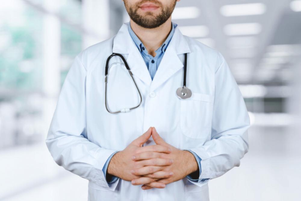 Confident Male Doctor in White Coat with Stethoscope in Hospital Environment Confident Male Doctor in White Coat with Stethoscope in Hospital Environment