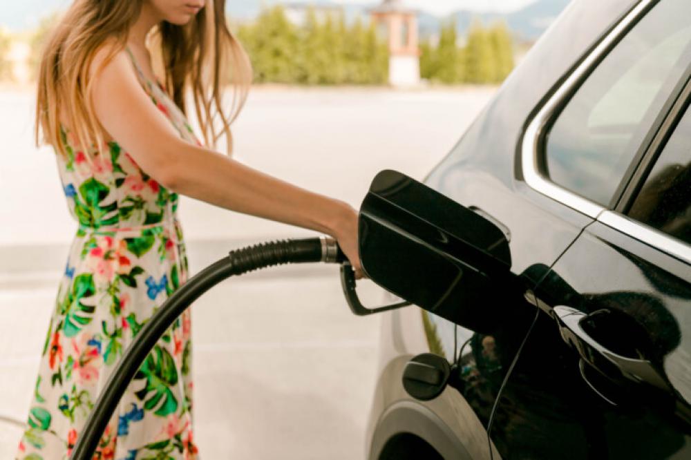 Young Woman Refueling Car at Gas Station on a Sunny Day Young Woman Refueling Car at Gas Station on a Sunny Day