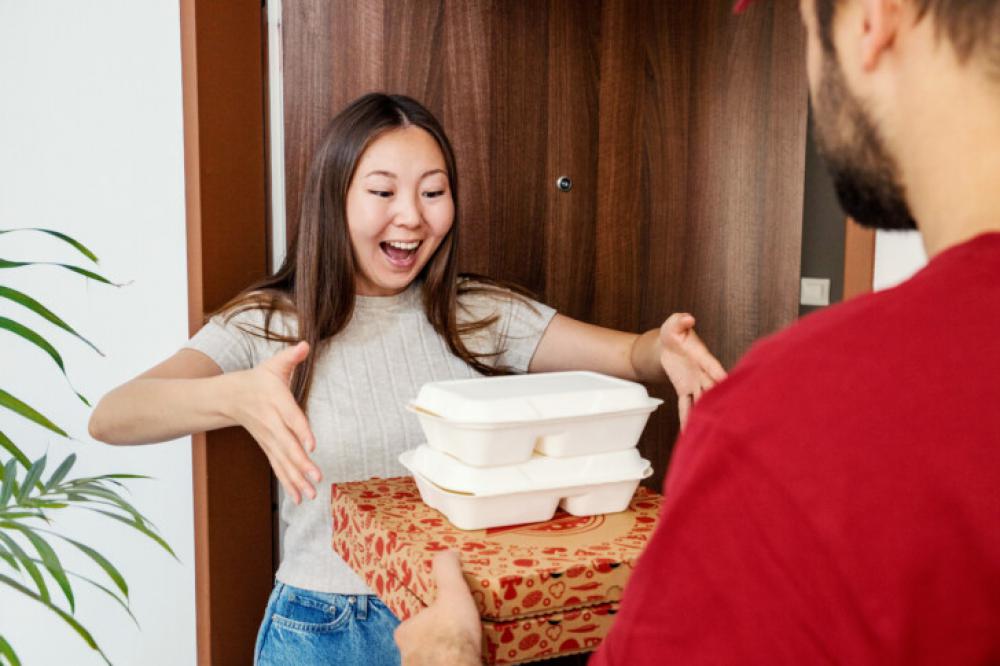 Excited Woman Receiving Food Delivery at Home Door from Courier Excited Woman Receiving Food Delivery at Home Door from Courier
