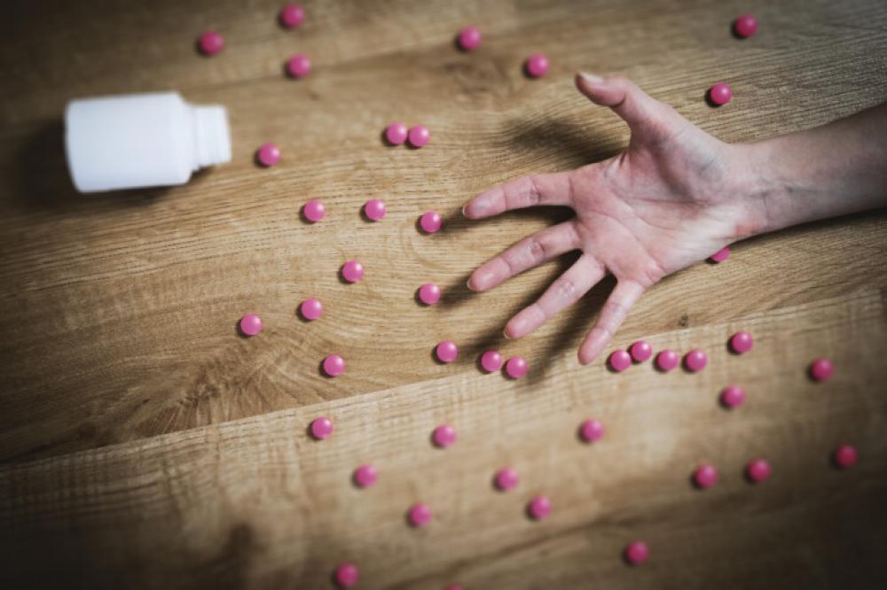 Hand with spilled pills on the floor – drug overdose concept Hand with spilled pills on the floor – drug overdose concept