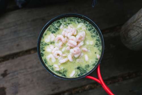 Cooking shrimps with spinach outside camping