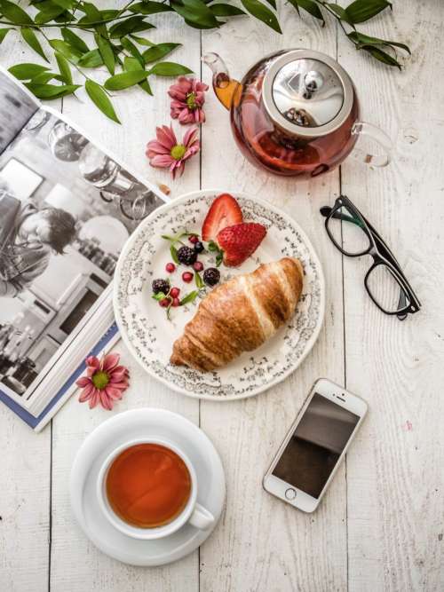 Relaxing with book, tea, croissant and berries