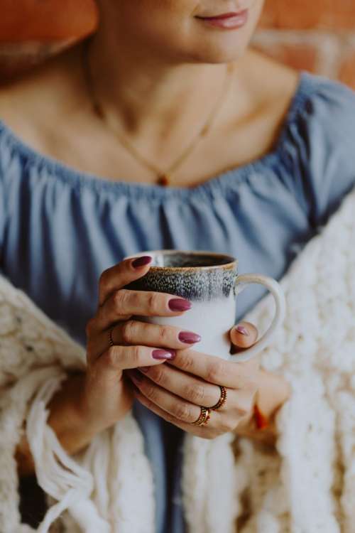 Woman in a warm blanket holding a cup of coffee