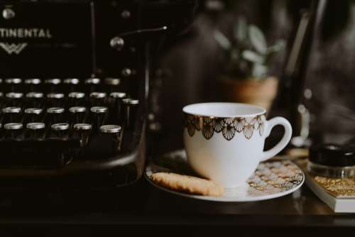 Writing on a typewriter with coffee and biscuit