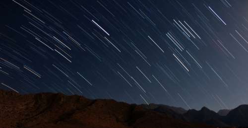 Star trails over the mountains in night sky free photo