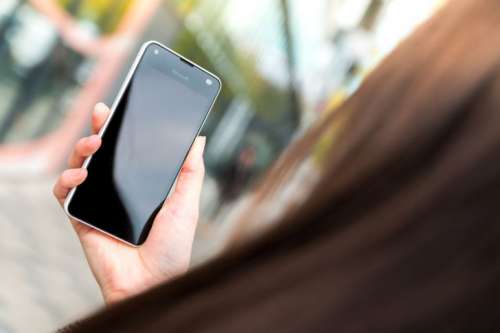 Woman uses her modern smartphone on the street.