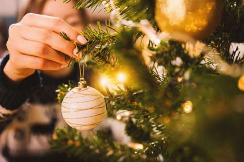 Woman decorating Christmas tree with baubles