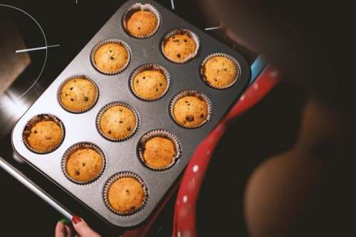 Baking pan with fresh muffins and young girl