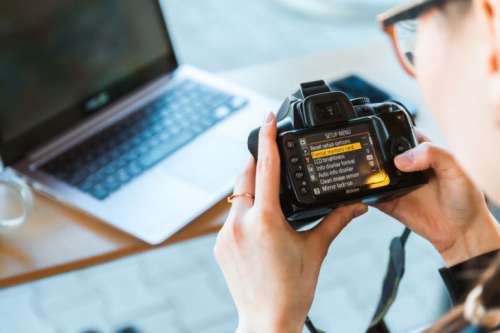 Photographer changes settings his DSLR camera at the modern office