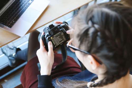 Young girl check her DSLR camera at cafe