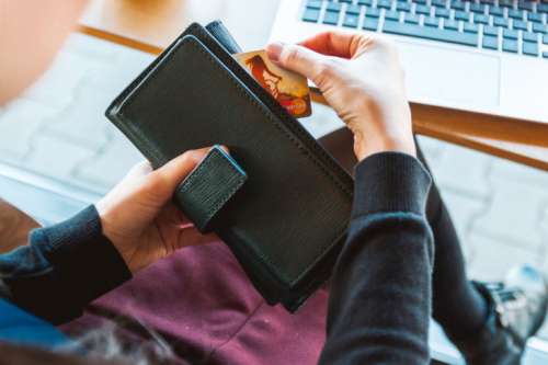 Woman with wallet is using her credit card for shopping online