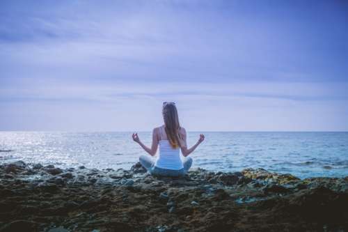Young woman doing yoga on a rocky seashore.