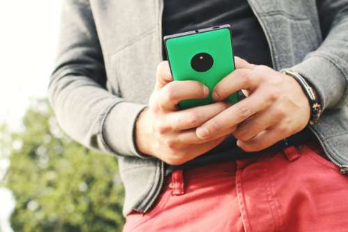 Boy holding a green smartphone in the hands