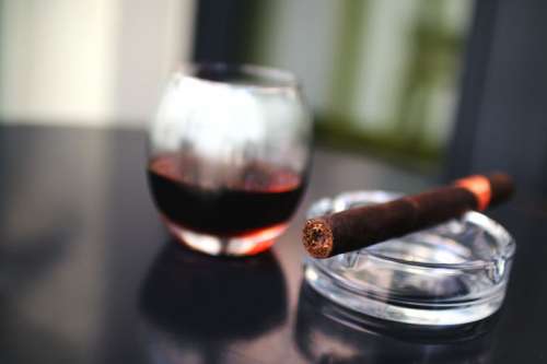 Cigar with a glass of alcohol on a black table