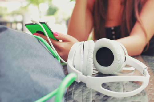 Headphones on the table and in the background girl with a smartphone