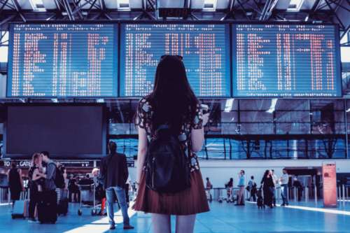 Young woman with bag checking flight timetable in international airport