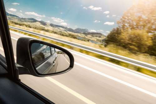 The reflection in the rear-view mirror of car in motion