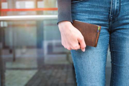 A young woman is holding her wallet outdoors