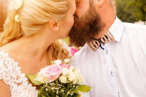 Kissing wedding couple in summer nature close-up portrait