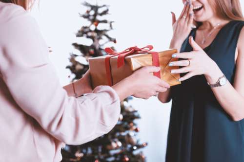 Happy and surprised woman receiving a gift. Merry Christmas