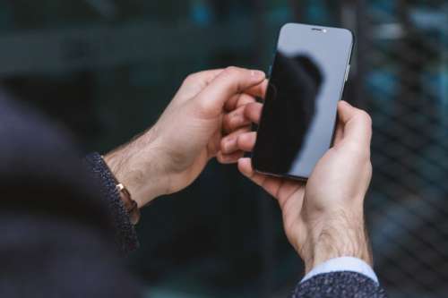 Man hands holding modern smartphone with blank black screen