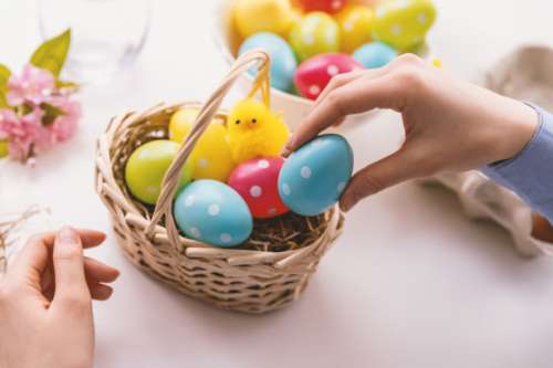 Happy Easter! Young woman is giving painted eggs to basket