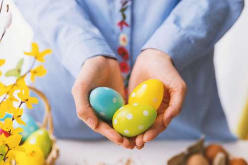 Hands holding modern painted easter eggs.