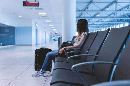 Young girl with long hair is sitting in airport.