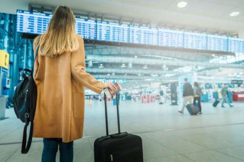 Young woman in coat with luggage at the airport