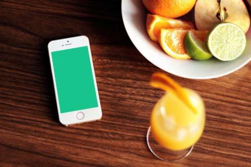 Smartphone, a bowl of fruit and a drink on the wooden table