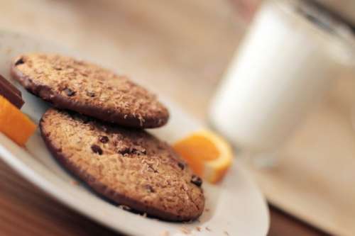 Cookies with chocolate on a plate and a glass of milk in the background