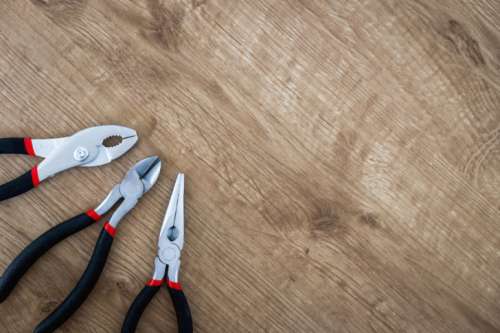 Set of pliers tools on wooden board