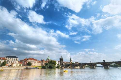 Beautiful day with blue sky and clouds in Prague and a view of the bridge from the river