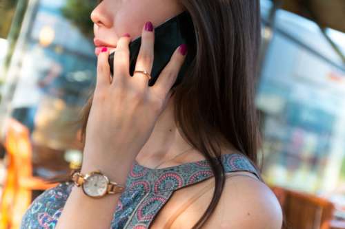Beautiful and elegant young lady phones with a black smartphone