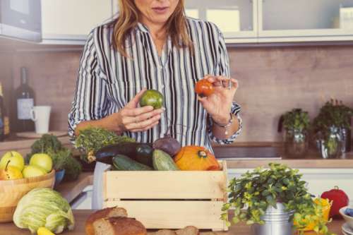 Woman with a pile of fresh vegetables in the kitchen