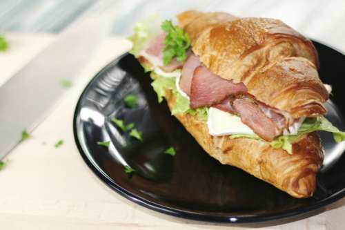 Fresh sandwich with ham and vegetables on the black plate