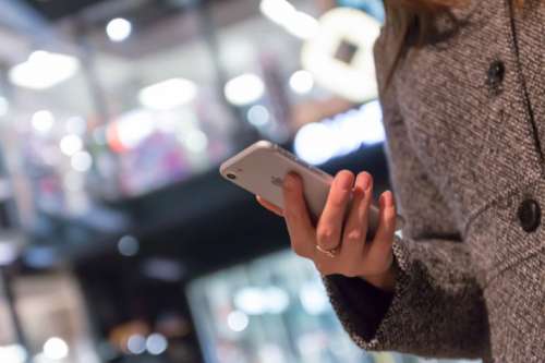 Girl uses a smartphone in the winter in front of a shopping center