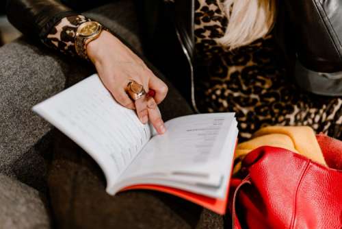 A woman with a large ring and a golden watch writes down in the calendar