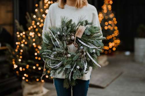 The woman is holding a Christmas wreath in her hands