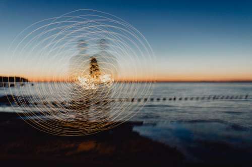 Light painting. The man waving fairy lights at the sea at sunset.